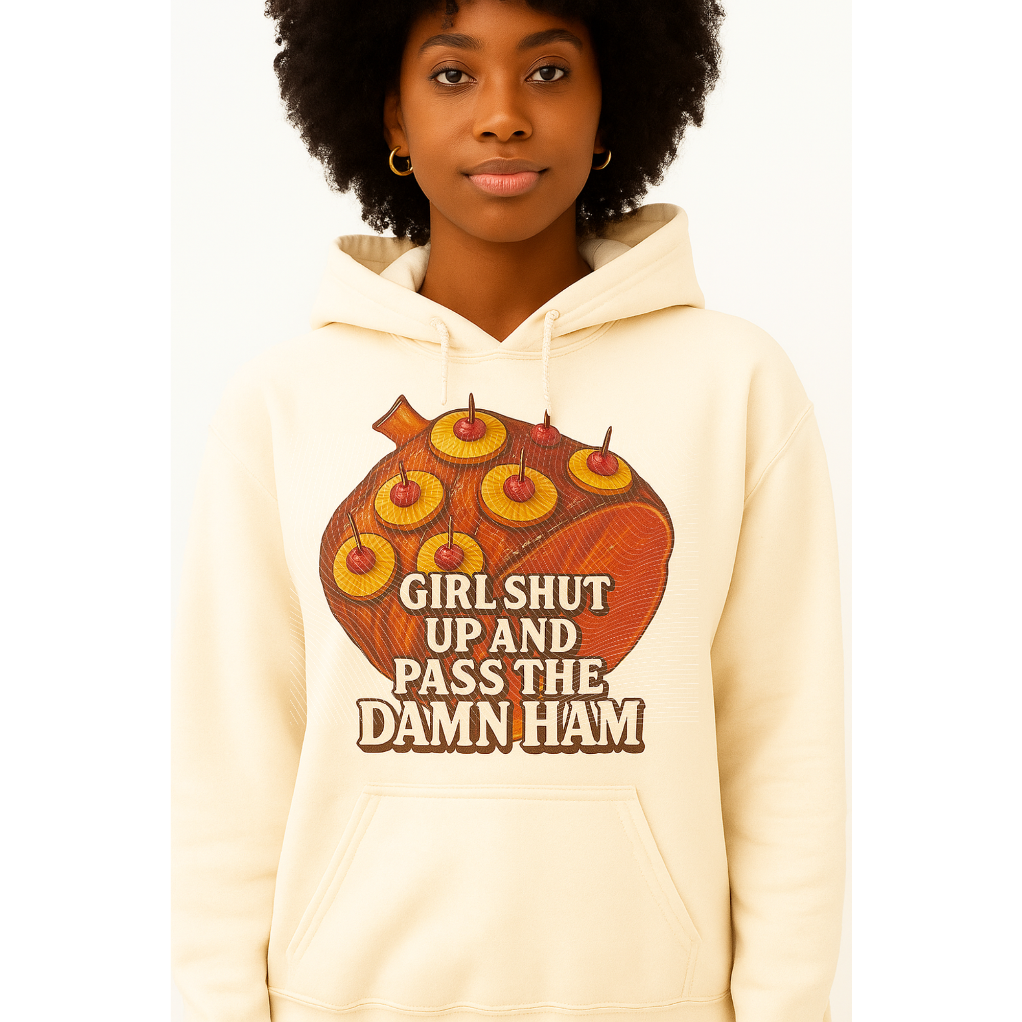 Person wearing a beige hoodie with a graphic design and text on a white background. It has a picture of a ham and says Girl Shut Up And Pass The Damn Ham.